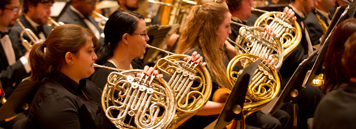 Three members of the Buffalo State Wind Ensemble playing the french horn.